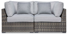 This cool, casual outdoor chair will raise the comfort level and visual appeal of your outdoor living space. Made of handwoven wicker in neutral tones of light and dark gray, the cushioned corner chair blends beautifully into your lanai or pool and patio 