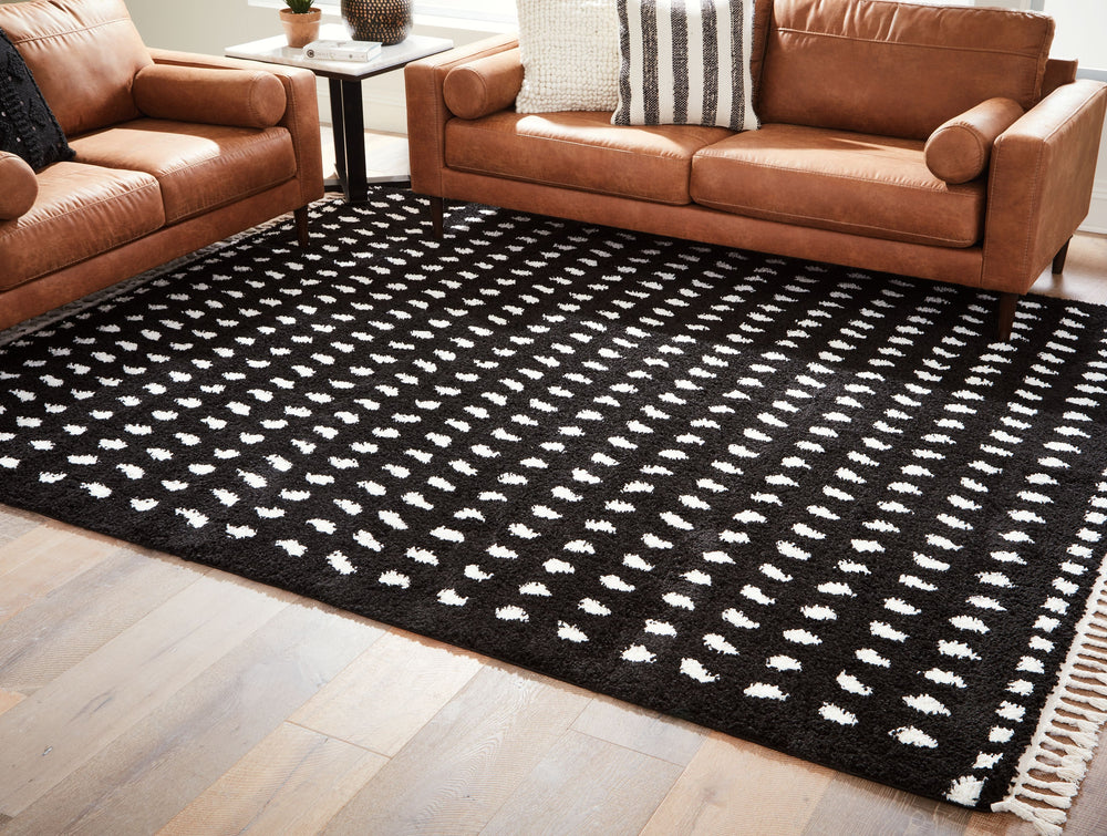 Sink your feet into this modern area rug. Offering a luxurious shag with woven dot design in black and white, this rug adds sophistication to any space without sacrificing comfort or durability. Finished with a braided tassel edge completing the design, t