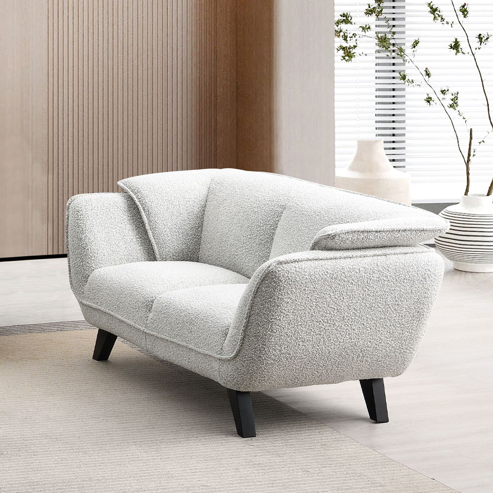Unwind in the sophisticated charm of the Manon sofa, draped in light gray fabric. Accompanied by plush pillows, it offers a perfect blend of comfort and style. This sofa invites cozy conversations and serene relaxation, making it an ideal addition to any 