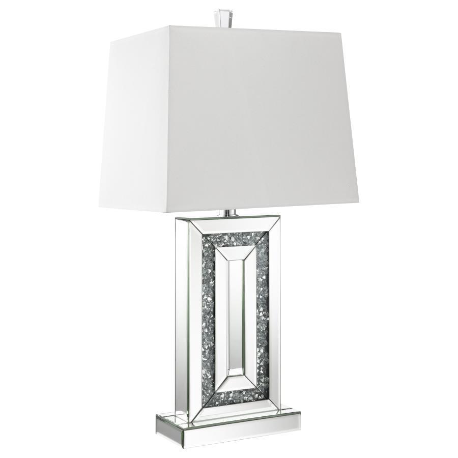 This modern table lamp features a rectangular base framed with beveled mirrored panels and sparkling crushed acrylic crystal inlay. Its geometric design delivers bold symmetry and a touch of glamour, anchored by a crisp white shade that softens the light.
