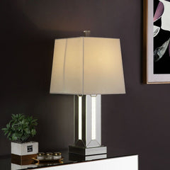 Brighten up your room in sophistication style with this Noralie Table Lamp. Fitting in a variety of design aesthetic, this piece features a classic drum shaped shade. The table lamp showcases a cuboid mirrored base with clear glass and faux stones inlayed
