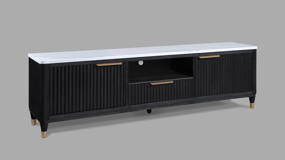 This entertainment console brings modern luxury and sleek sophistication to any living space. Featuring a striking contrast of a black, fluted wood facade with a pristine white faux marble top, this piece embodies refined elegance. Brass-tone accents and 