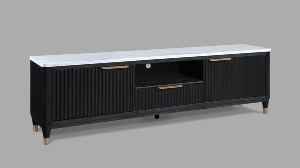 This entertainment console brings modern luxury and sleek sophistication to any living space. Featuring a striking contrast of a black, fluted wood facade with a pristine white faux marble top, this piece embodies refined elegance. Brass-tone accents and 