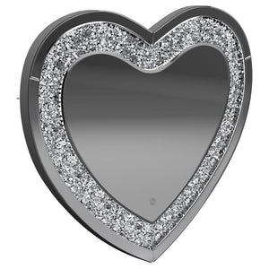 This heart-shaped wall mirror adds sparkle and function to glam-inspired spaces. Framed with mirrored glass and outlined by faceted acrylic crystal inlay, it delivers high-shine appeal. Integrated LED lighting enhances visibility for makeup, grooming, or 