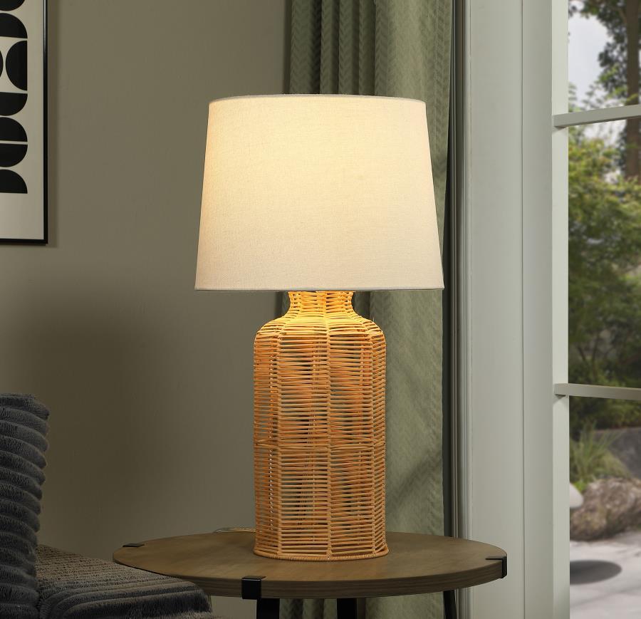 This table lamp seamlessly combines natural textures with modern elegance. Featuring a handcrafted rattan base in a cylindrical shape, it exudes a warm and organic appeal. The neutral fabric shade beautifully complements the rattan, softly diffusing light