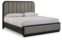 Inspired by art deco design, this softly shaped California king upholstered panel bed makes a lasting impression in a simply stunning way. Its magnificent curved silhouette is enhanced by a rich layered black finish on the textured wood grain surface. The