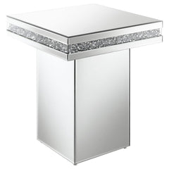 Showcase sculptures and decor on this stunning, modern glam accent table. A square table sits on a tall square pedestal for an edgy, bold expression. Smooth mirror trim and surfaces cover every edge, creating a sleek flair. Glittering acrylic crystals lin