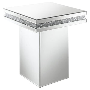 Showcase sculptures and decor on this stunning, modern glam accent table. A square table sits on a tall square pedestal for an edgy, bold expression. Smooth mirror trim and surfaces cover every edge, creating a sleek flair. Glittering acrylic crystals lin