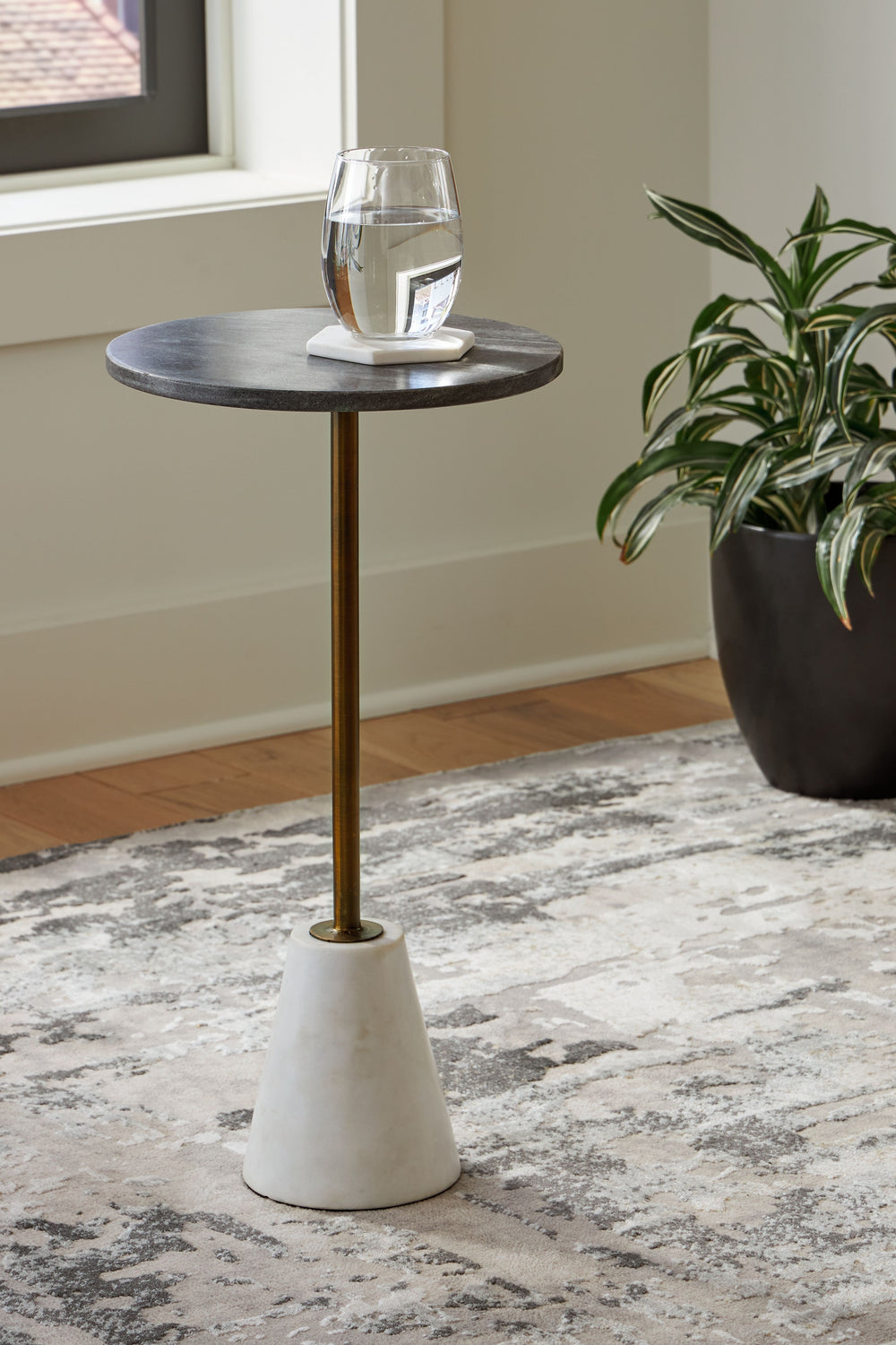Marvel at the marbled mastery of this high-end accent table. Made of beautiful black and white marble, the round tabletop is supported by a sturdy goldtone pedestal on a white marble base. With a sleek, tapered profile, this space-saving table is striking