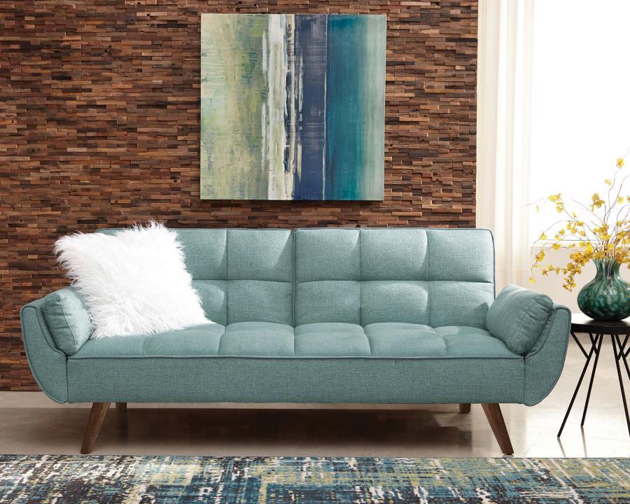 Add a pleasing pop of color to your living room or den. This charming sofa bed is upholstered with a soft, woven fabric in a stunning shade of turquoise blue. A biscuit-tufted seat and back give it a touch of updated glamour. With a soft, fuzzy white acce