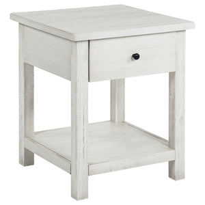 This rustic end table merges classic style with practical storage, making it a charming focal point in any living room. Built from pine wood and reinforced with engineered wood, its square silhouette highlights a subtle, timeworn aesthetic. An integrated 