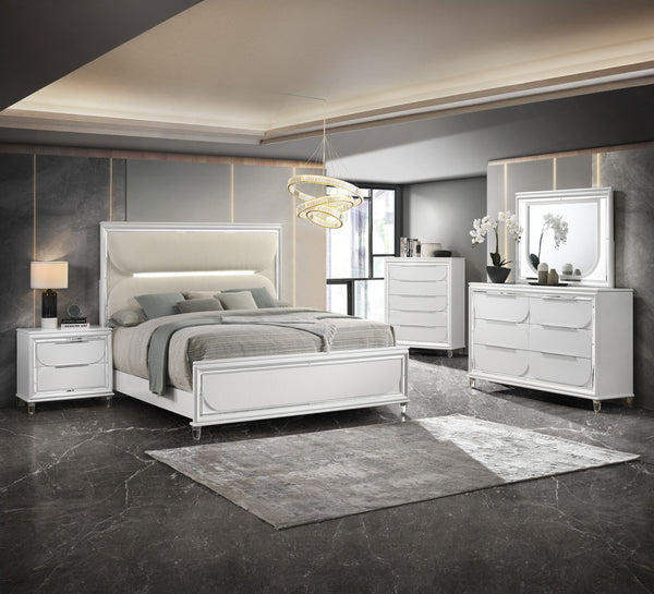 This bedroom set is a sophisticated fusion of modern design and luxurious comfort. Each piece boasts a bright white finish, accented with sleek mirrored trim that adds a touch of shine and refinement. The centerpiece is an opulent bed with an oversized he