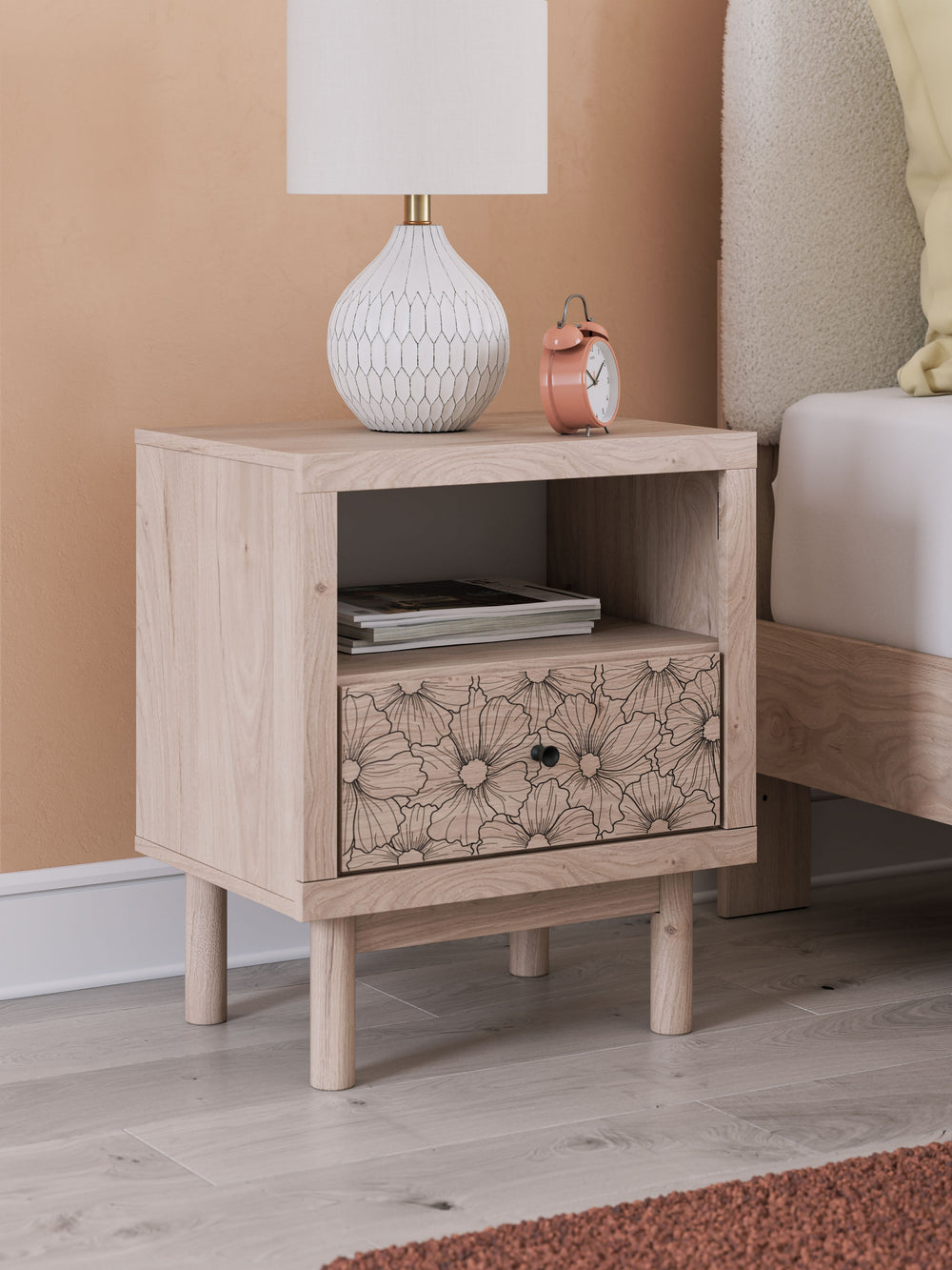 Looking for a nightstand that-'s both playful and practical for your little one? This piece is just the ticket. Its charming design and light wood finish create a whimsical and inviting atmosphere. A floral-patterned drawer adds a free-spirited vibe and p