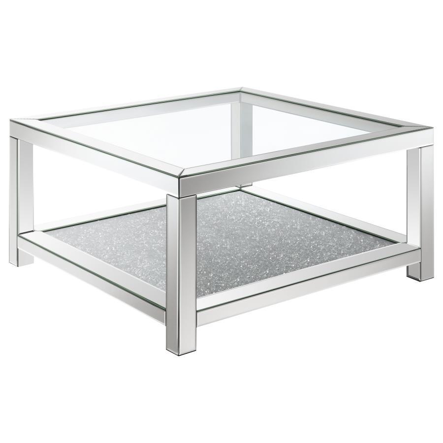 This glam mirrored coffee table is the epitome of Hollywood Regency vibes. Designed with beveled mirror trim and a tempered clear glass top, it offers modern flair and sophistication. The sparkling acrylic jewel-encrusted bottom shelf adds a dazzling touc
