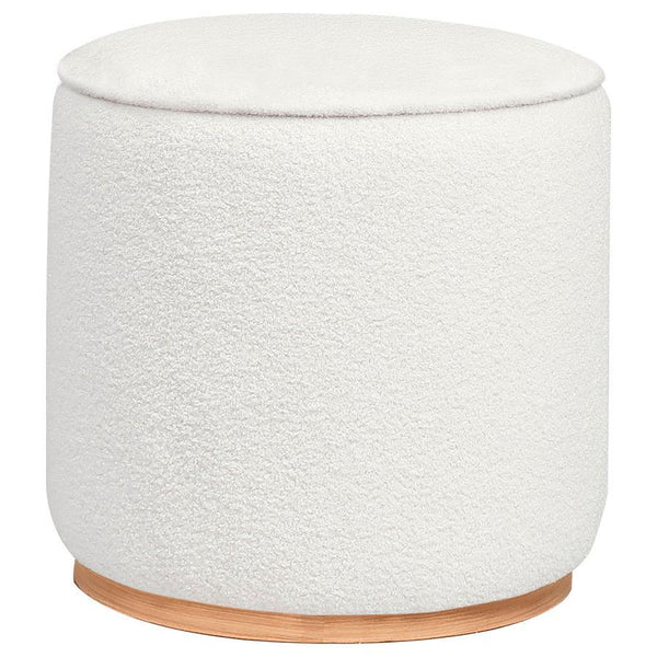 Add a touch of playful luxury to your living space with this round upholstered ottoman, swathed in sumptuous faux sheepskin that invites you to touch. Resting on a metal base that-'s been expertly finished to emulate the warm, natural allure of wood grain