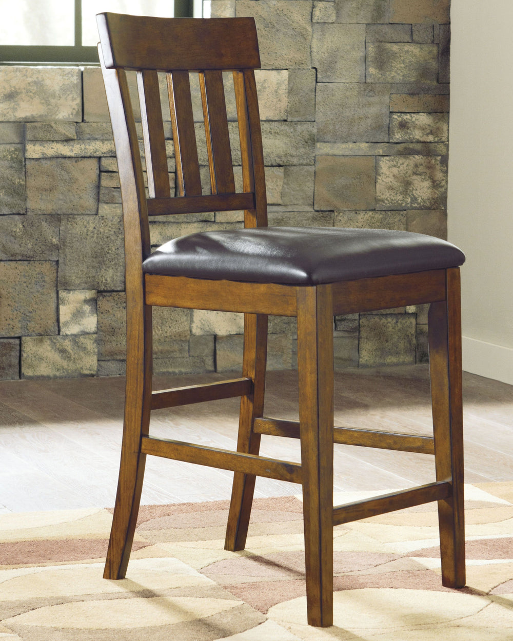 Sleek lines and comfortable cushioning combine to make this upholstered bar stool the favorite seat at the table. Traditional shaker design is given a vintage treatment with the rustic, burnished finish. Faux leather upholstery easily wipes clean.<br><br>