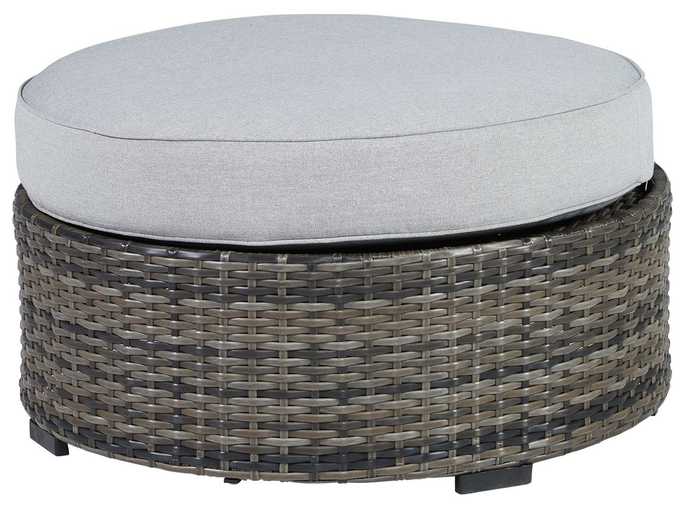 This cool, casual outdoor ottoman will raise the comfort level and visual appeal of your outdoor living space. Made of handwoven wicker in neutral tones of light and dark gray, the cushioned ottoman blends beautifully into your lanai or pool and patio are