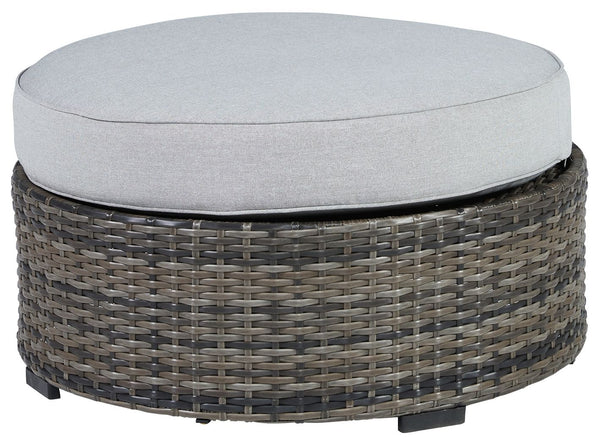 This cool, casual outdoor ottoman will raise the comfort level and visual appeal of your outdoor living space. Made of handwoven wicker in neutral tones of light and dark gray, the cushioned ottoman blends beautifully into your lanai or pool and patio are