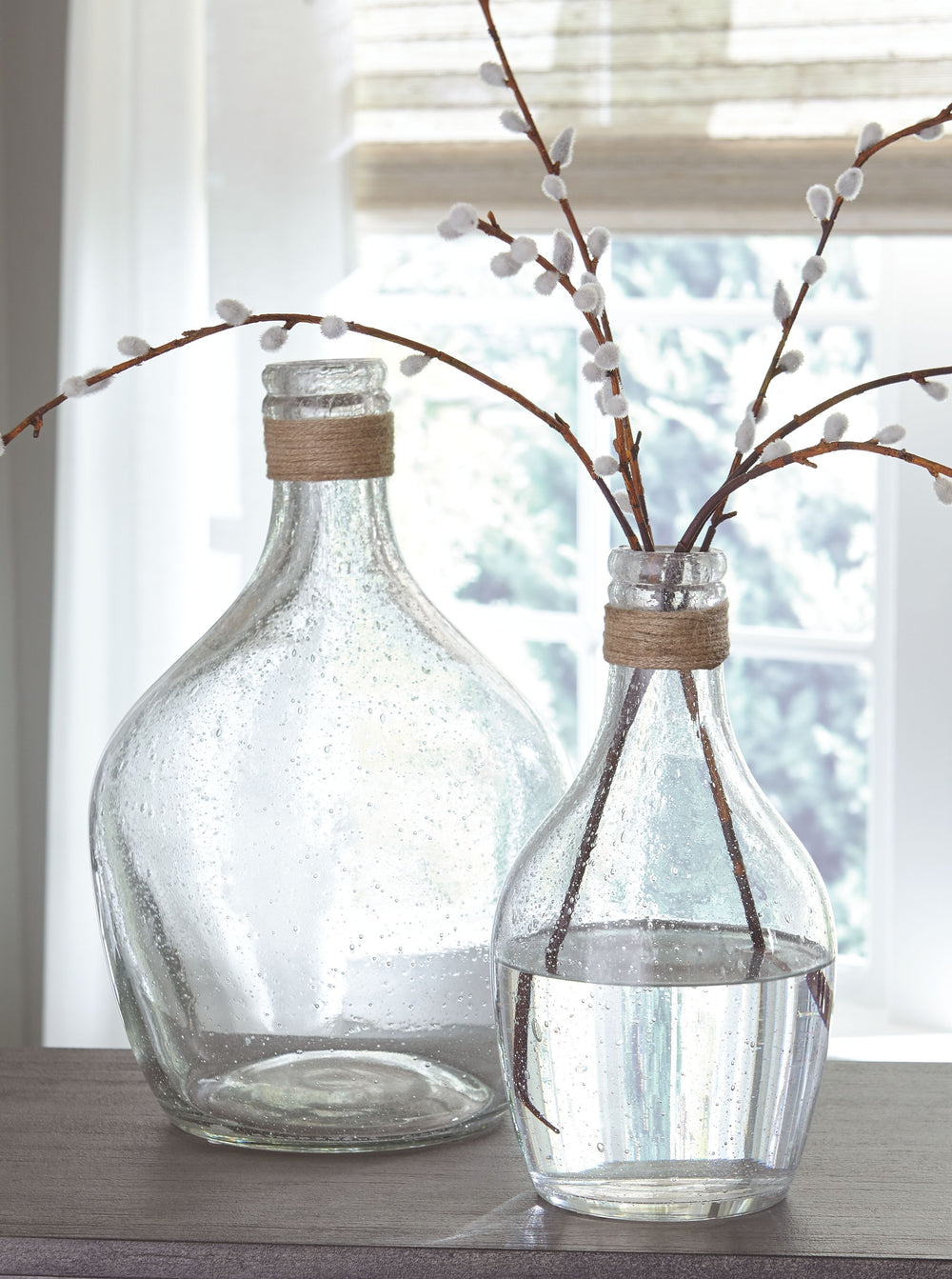 This 2-piece vase setâ€™s versatility is a stylistâ€™s dream. Light brown rope ties around the top of the bottleneck design. Seeded finish brings texture to the clear glass. Drop in faux cotton stems for a vintage or modern farmhouse look.<br><br><b>Addit