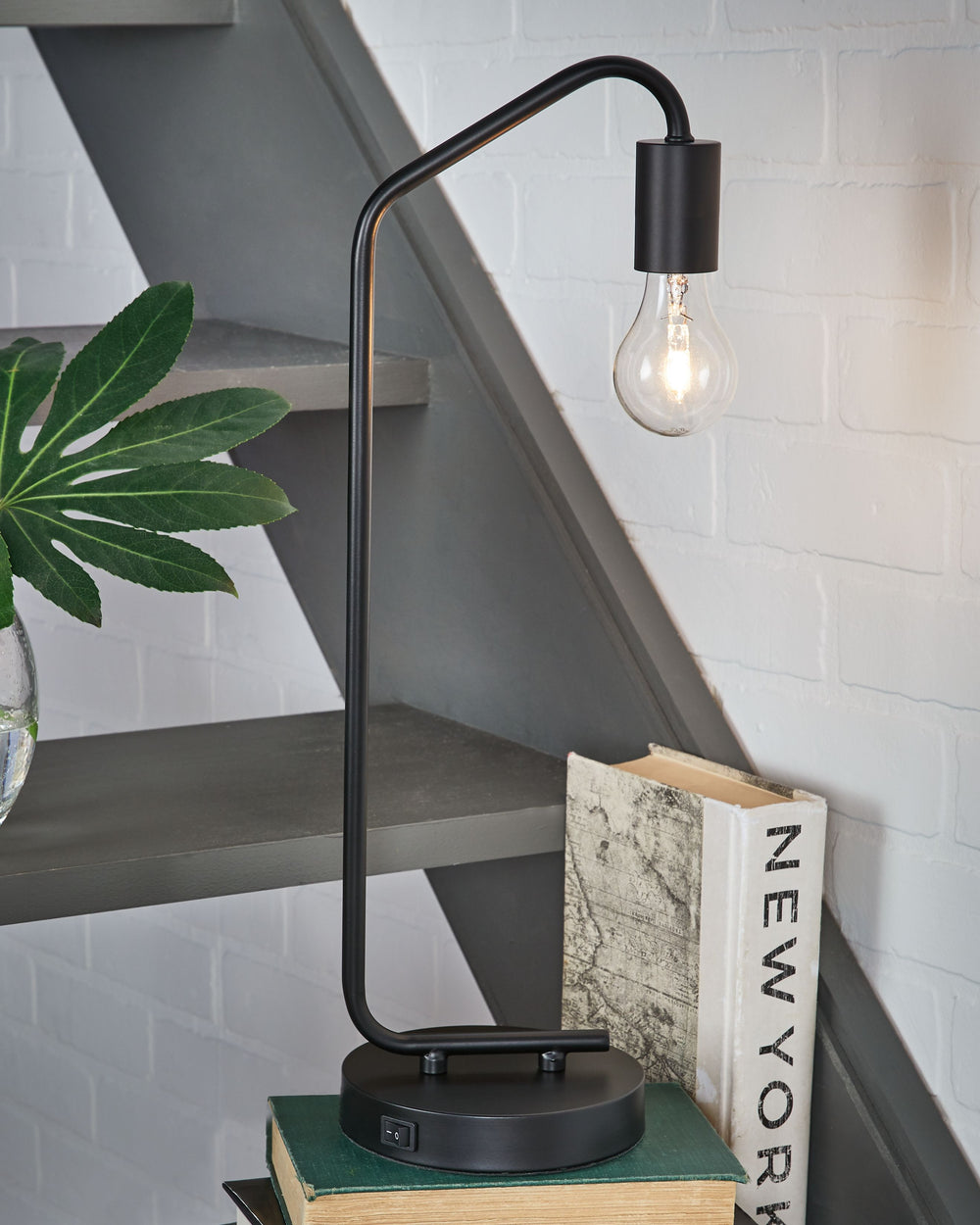 Brilliant in its minimalist form, this desk lamp suspends its exposed bulb in one sleek swoop. Constructed of metal, the compact, lightweight lamp is portable and features a single USB charging port. We see it glowing bedside, on a bookshelf or on either 