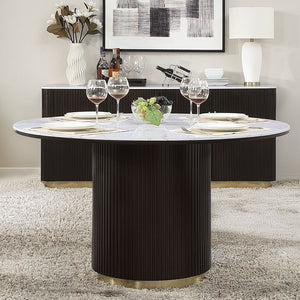 The Clayten collection features a round dining table with a fixed marble top, supported by a single pedestal base adorned with metal trim. Accompanied by upholstered chairs and a server with sleek metal legs, this set combines modern elegance with timeles