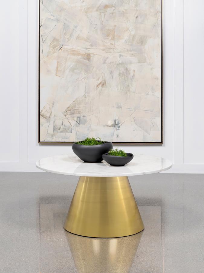 This modern coffee table exudes luxury with its gorgeous white marble top and conical metal base. The round profile creates a unifying, sophisticated focal point in any living room. Crafted from genuine marble, the tabletop radiates elegance, while the br