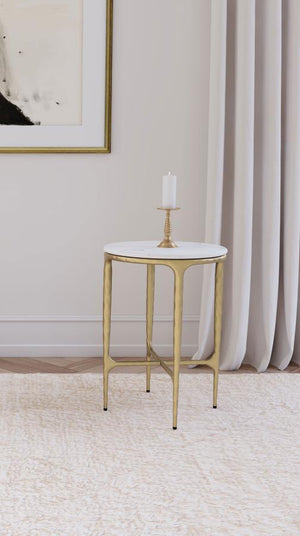  where luxurious materials and sculptural design meet. The table boasts a genuine white marble top that sits gracefully atop a hand-hammered steel frame with a rich gold finish. 