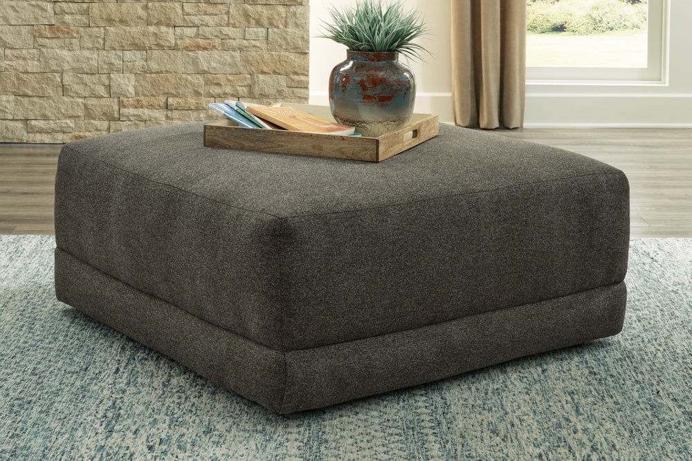 Architecturally inclined with its gently curving profile, this oversized accent ottoman is stunning from all angles. Acting as the focal point in a neutral space, the granite-hued upholstery also creates a blank canvas for adding pops of color.<br><br><b>