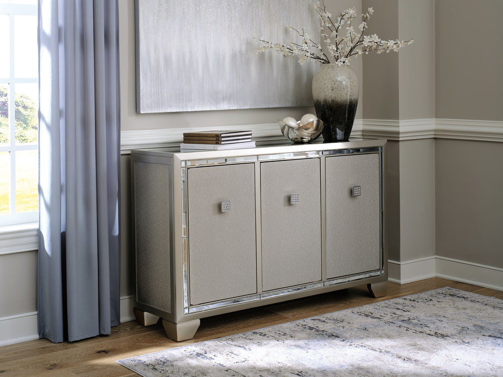 Reflect your love for contemporary style with this accent cabinet. It features a mirrored top and beveled mirror accents, adding both light and a touch of glam to your space. Decorated with faux crystal and chrome-tone pulls, the textured silvertone door 