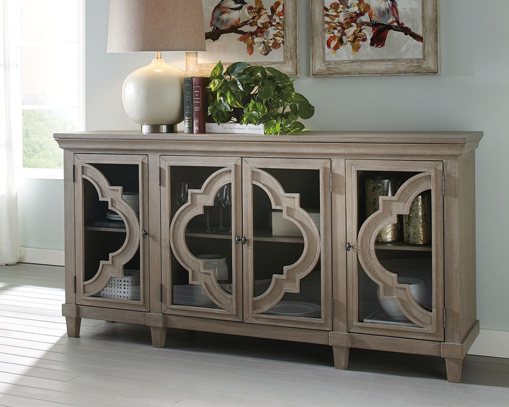 Wowing with exquisite quatrefoil framing, made all the more dramatic with the contrast of clear glass, this 4-door cabinet serves up an easy-elegant aesthetic sure to satisfy. The light and lovely finish brings a relaxed sensibility to the scene.<br><br><