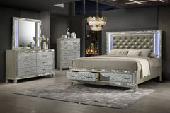 Embrace the allure of the Radiance Queen 4 Piece Bedroom Set in Platinum Silver, featuring a storage bed, 6 drawer dresser, lighted mirror, and 5 drawer chest, meticulously crafted for unmatched stability and durability from a blend of solid rubberwood an