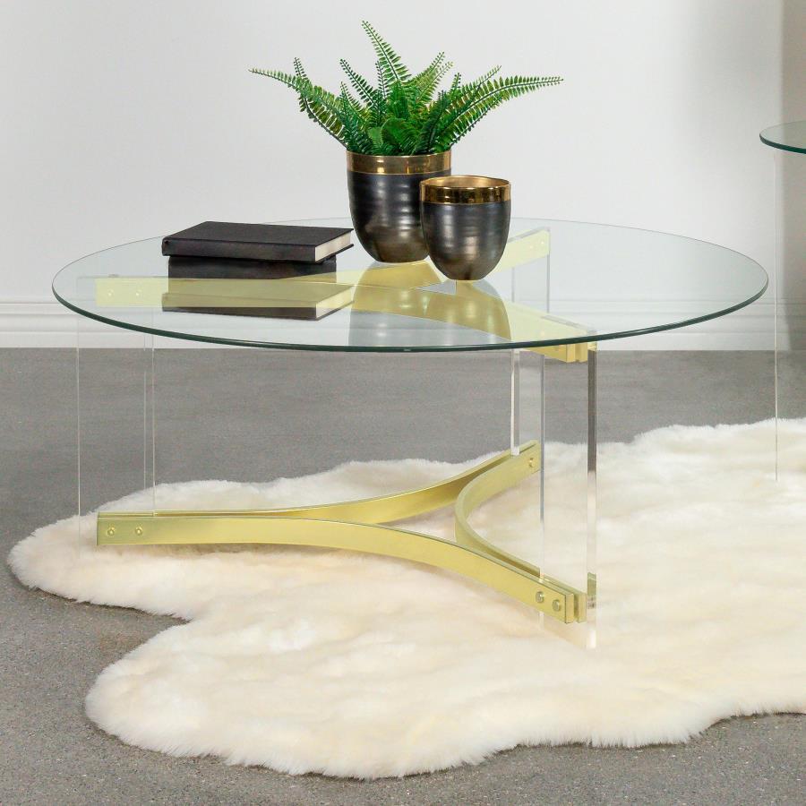 This round coffee table features a clear tempered glass top, offering an elegant surface for any living room. The sleek, clear acrylic legs enhance the modern design, while the matte brass electroplated frame provides a luxurious touch. Its minimalist con