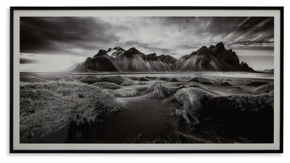 If you have your sights set on a striking landscape, this wall art is a natural wonder. Staggeringly beautiful, the framed black and white print showcases majestic mountains and a meandering stream. This moody and marvelous piece adds an air of dramatic b