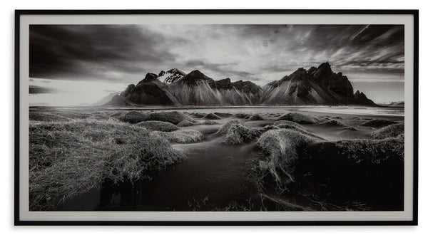 If you have your sights set on a striking landscape, this wall art is a natural wonder. Staggeringly beautiful, the framed black and white print showcases majestic mountains and a meandering stream. This moody and marvelous piece adds an air of dramatic b