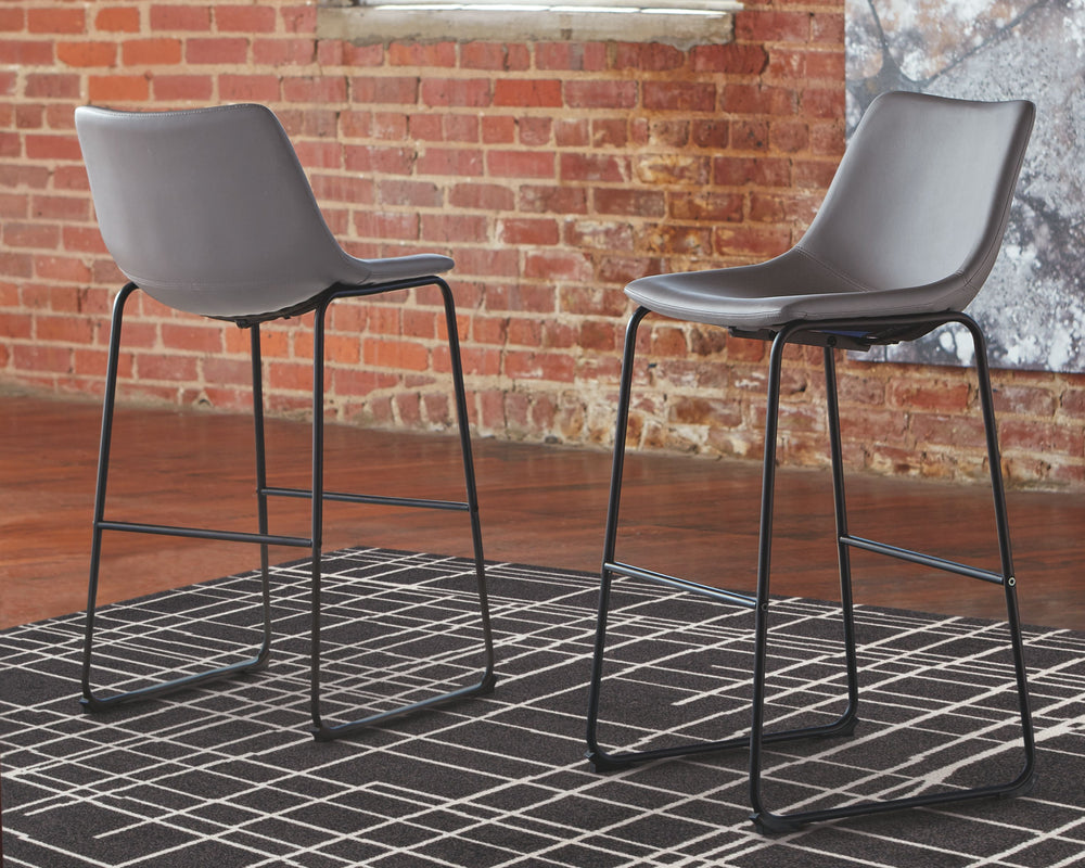 With its distinctive contoured bucket seat and tubular metal base, this bar stool serves up a fresh twist on mid-century inspired style. Chic gray faux leather upholstery adds to the aesthetic. What a timeless look for eat-in kitchens and casually cool di
