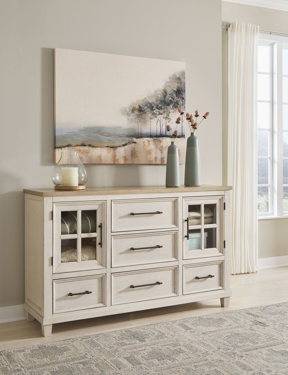 This dresser elevates the art of modern farmhouse design. Its two-tone aesthetic blends antiqued white and light grayish brown for a charming finish. Framed drawer fronts and windowpane cabinets lend a country feel. Conveying a feeling of relaxed comfort,