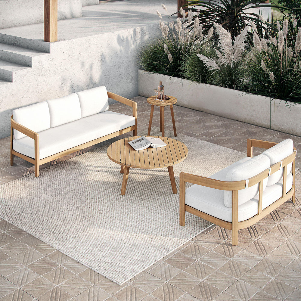 The Wesley 4-Piece Wood Patio Set, featuring a spacious outdoor sofa, a cozy loveseat with plush white cushions, a coffee table, and an end table, effortlessly combines durability, comfort, and modern design for a stylish outdoor retreat. Expertly crafted