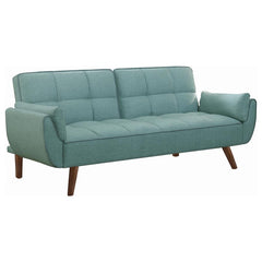 Add a pleasing pop of color to your living room or den. This charming sofa bed is upholstered with a soft, woven fabric in a stunning shade of turquoise blue. A biscuit-tufted seat and back give it a touch of updated glamour. With a soft, fuzzy white acce