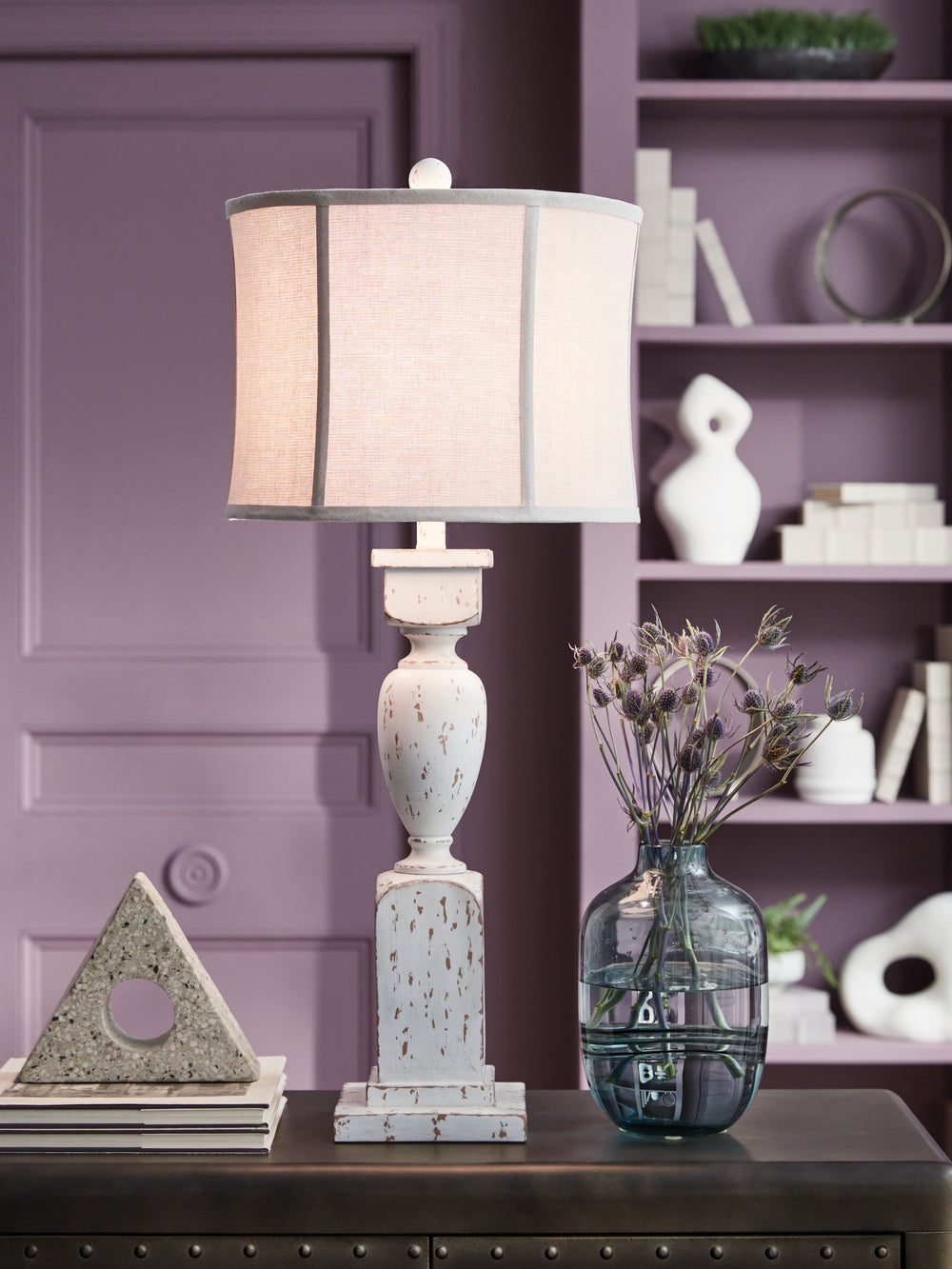 This table lamp takes a classic approach to tasteful lighting. Its detailed base ushers an air of elegance into your space with a graceful turn design. Outfitted with an antiqued white finish, it-'s right at home in traditional spaces. Pair with the match