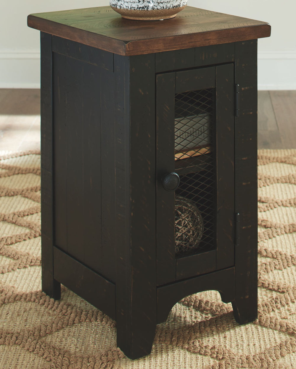 To those with an eye for the best in rustic farmhouse living, this two-tone chairside end table doubles up on charm. Designer touches include plank-effect styling, distress marks and a wire mesh door front for added character.<br><br><b>Additional Dimensi