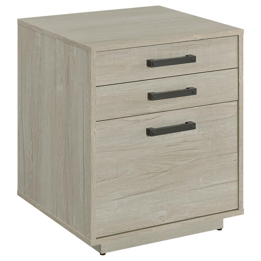 Free up desk space with this contemporary file cabinet, featuring a lovely whitewashed grey finish across its boxy frame and three drawers. Along each drawer is a slim gunmetal finished pull that presents an industrial modern flair to a transitional home 