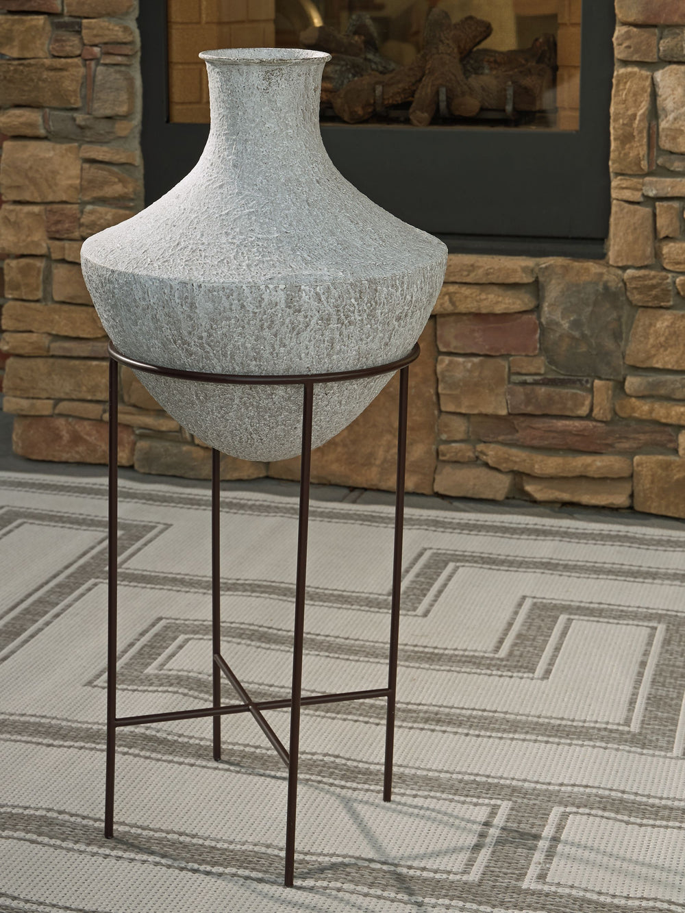 Take an effortlessly inviting approach to floor decor. This vase-'s distressed, textured look in a neutral hue pairs with a variety of casual color palettes. An espresso brown stand adds charming contrast to the look. And this vase enthusiastically welcom