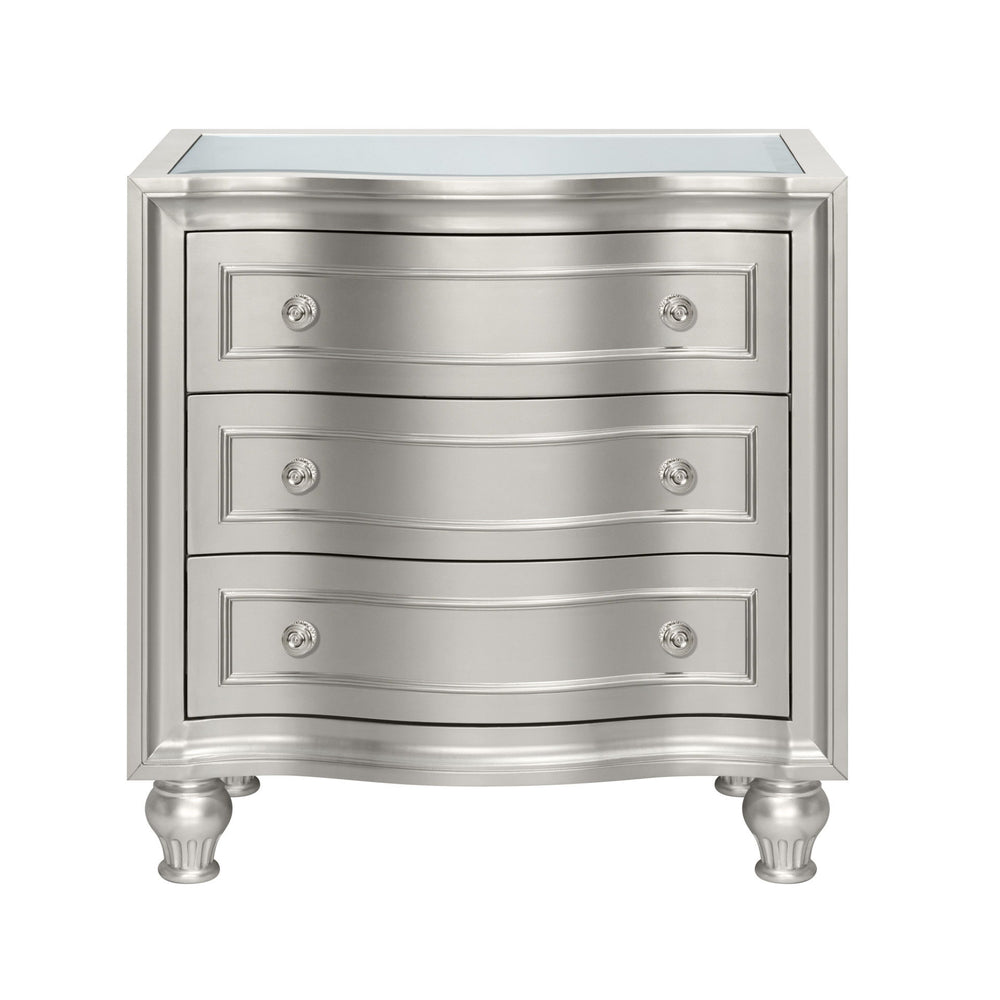 Introducing the Reflection Nightstand in Silver, expertly crafted from solid Pine and high-quality manufactured wood to ensure enduring strength and durability. Its glamorous matte silver finish exudes sophistication, accentuating the mirrored top and sil