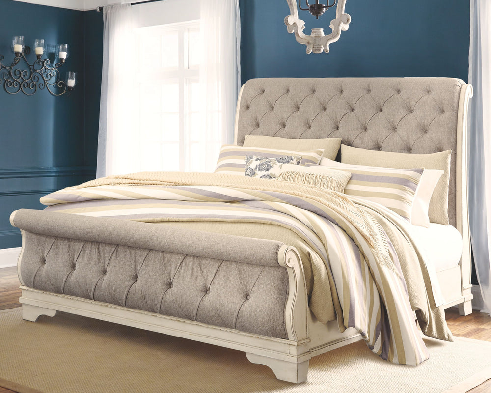 Elevating the art of traditional cottage styling, this California king upholstered sleigh bed is your dream bedroom retreat realized. A curvaceous beauty, this brilliant upholstered bed wows with a distressed chipped white finish for heirloom appeal. Deep