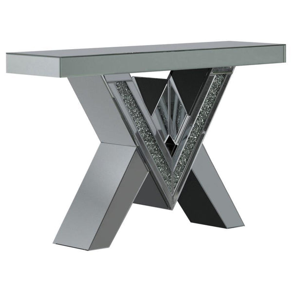 This mirrored console table boasts a striking V-shaped base with angular design elements, featuring inlays of sparkling acrylic crystals. The geometric form is complemented by sleek mirrored surfaces that enhance its modern aesthetic. The design combines 