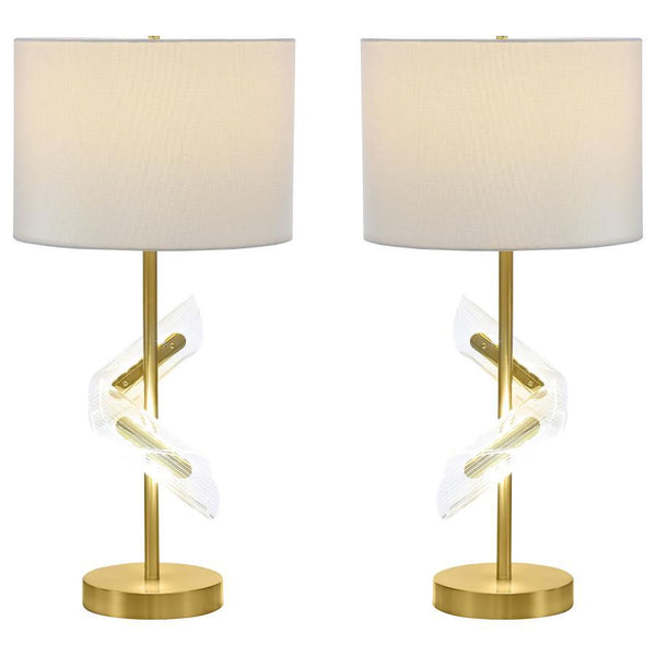 Designed to dazzle, this pair of gold table lamps features a clean drum shade paired with sculptural acrylic accents that wrap around the slender frame. A brilliant LED light glows from within the swirling acrylic, bringing dimension and ambient lighting 