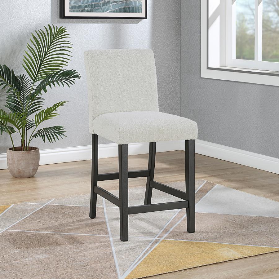 Elevate your dining experience with this chic counter height chair, a blend of simplicity and texture. Wrapped in the luxurious touch of boucle fabric, the chair offers a tactile feast, inviting guests to savor every second seated. Its silhouette stands t