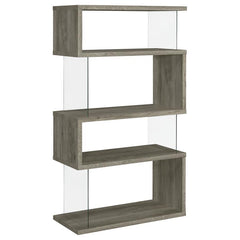 The asymmetrical zig-zag design of this contemporary bookcase creates a focal point in any room. Five open shelves in a light grey driftwood finish stack elegantly, supported by clear glass side panels that lend a modern flair to this furniture piece. Per