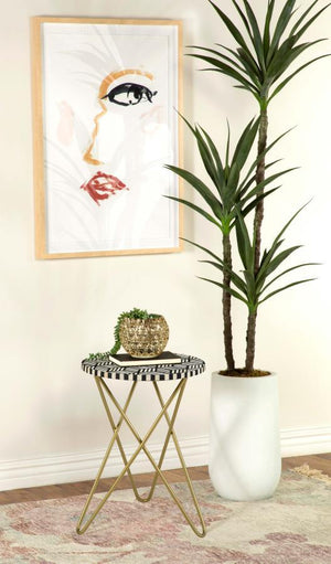  featuring a hand-inlaid bone and black resin mosaic that creates a striking geometric design. The round tabletop rests atop a sculptural butterfly-style hairpin metal base in a lustrous gold finish