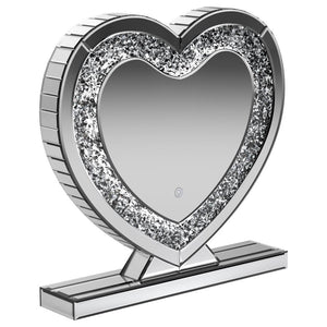 This heart-shaped table mirror blends glam style with practical lighting, perfect for vanities or dressing areas. The mirrored frame features an inset of faceted acrylic crystal inlay that catches light beautifully, while integrated LED illumination adds 